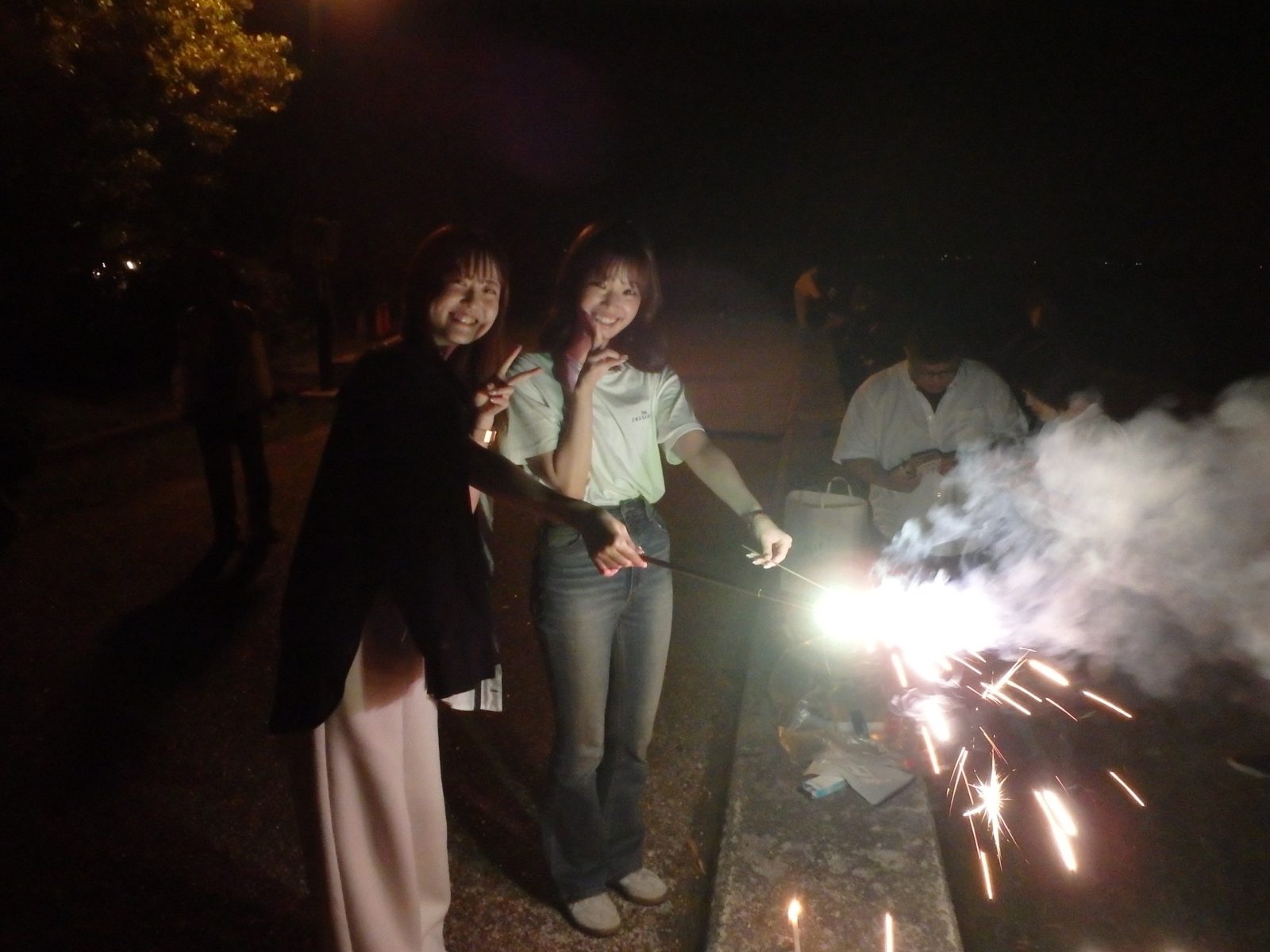 夜の湖畔で手持ち花火を楽しむ社員たち