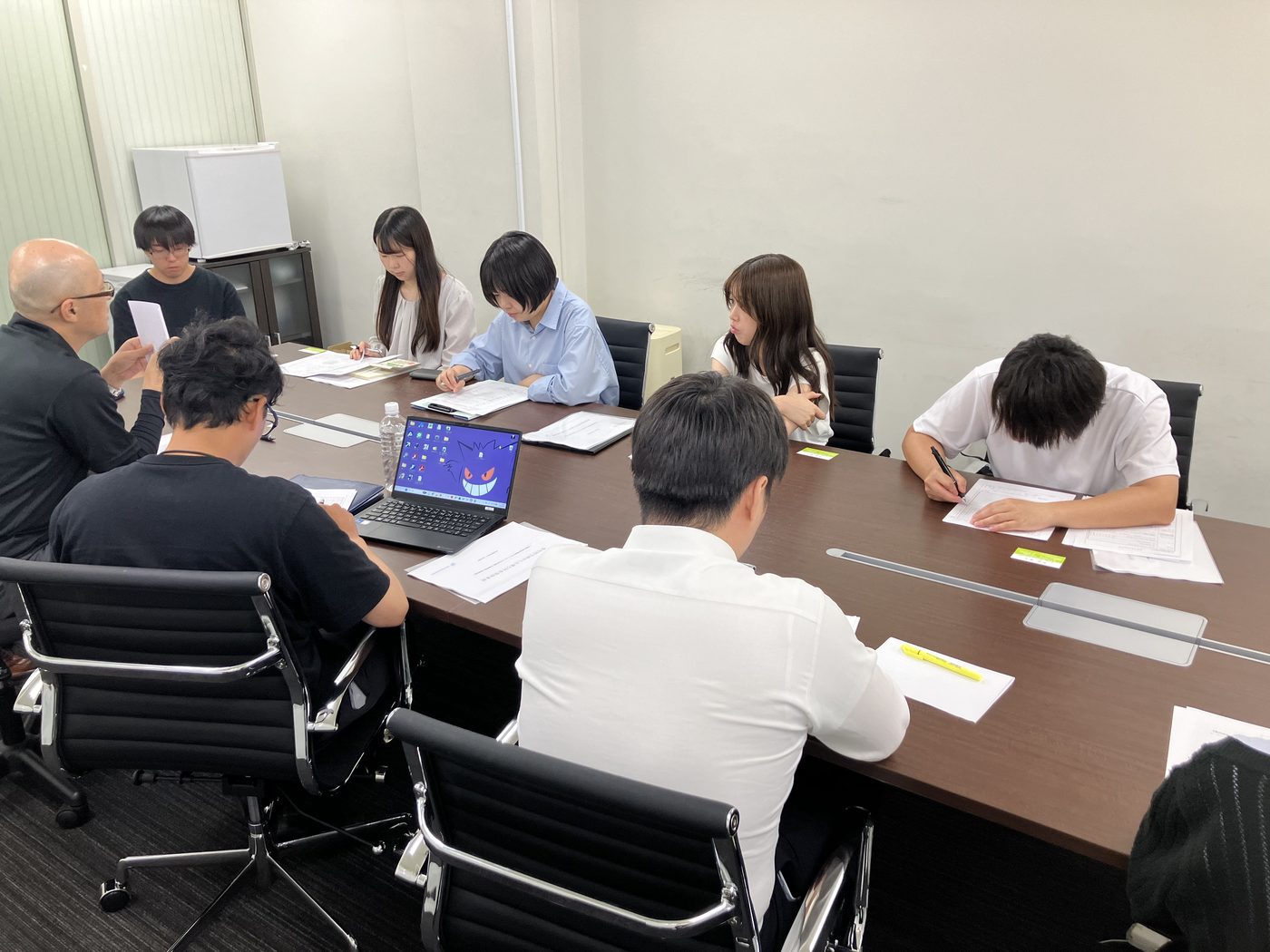 タックス・プラン税理士法人の外部研修の様子。会議室で講師を囲み、登記事項証明書(謄本)や定款の見方について担当者が学んでいる場面。