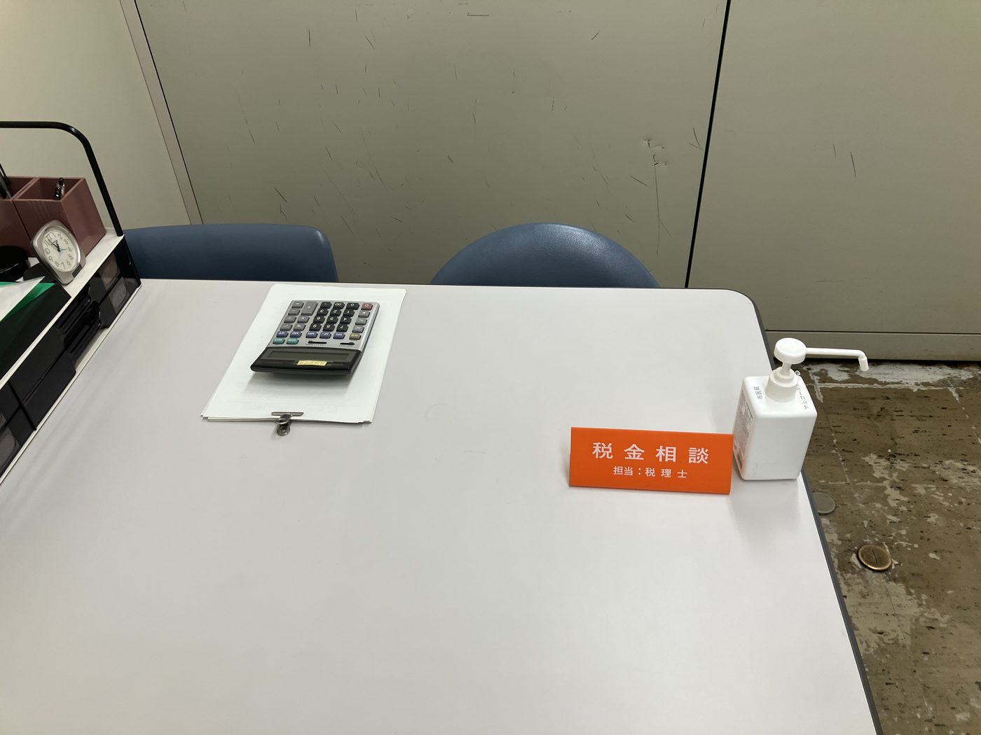 無料税務相談会の相談ブース。「税金相談 担当:税理士」の卓上表示と電卓が置かれた相談テーブル。
