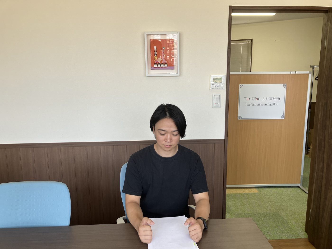 タックス・プラン税理士法人 入社3年目 玉田幹太が打合せテーブルで作成した資料・申告書をチェックする様子