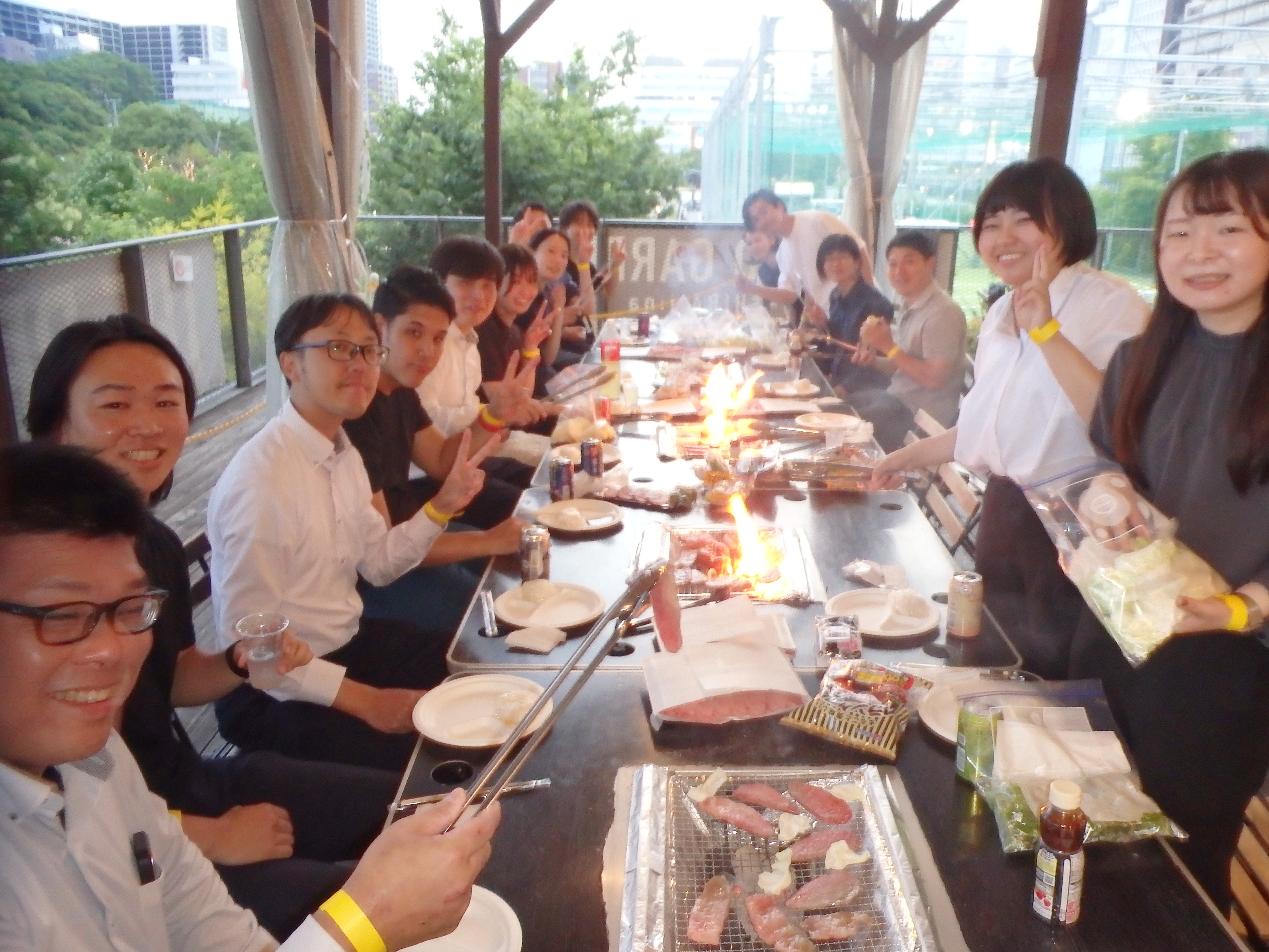 2026年5月開催 タックス・プラン税理士法人の社員BBQ大会。堺・大阪の本社・支店のスタッフが屋上テラスのBBQ会場に集まり、笑顔で食事と歓談を楽しんでいる様子。世代を超えて20名超の社員が参加し、和やかなチームの雰囲気が伝わる写真。